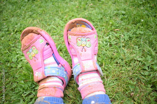 the legs of a little girl in sandals and socks are smeared with sand