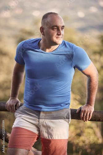 one young overweight man, 30-35 years, looking sideways, medium shot. outdoors nature.
