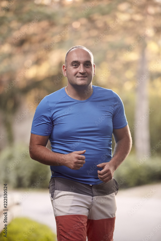 one young overweight man, 30-35 years, outdoors nature, jogging, medium shot.