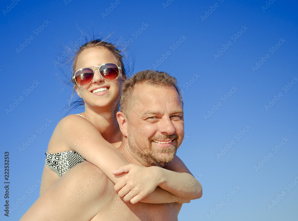 Dad and daughter teenager having fun at tropical beach during tropical summer vacation playing together at beach Dad and daughter teenager having fun at tropical beach during tropical summer vacation playing together at beach
