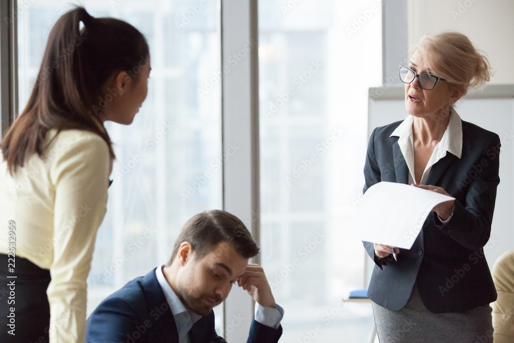Angry dissatisfied director business woman criticizing work, financial report accusing asian woman and man worker. Subordinate feels guilty and frustrated. Conflict, problems mistakes, dismiss concept