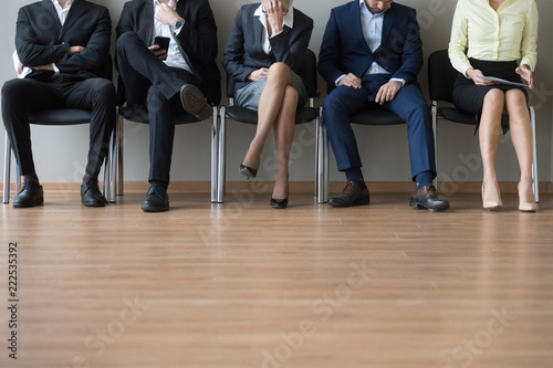 Close up businesspeople legs sitting in chair in queue wait job interview. Some of candidates sleeping, stressed tired and exhausted. Competition company position. Human resources, recruiting concept