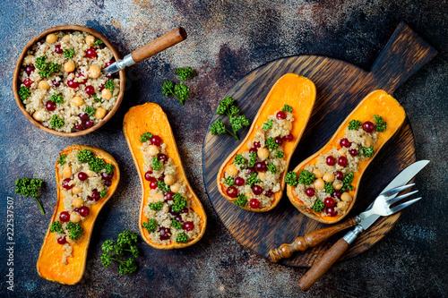 Stuffed butternut squash with chickpeas, cranberries, quinoa cooked in nutmeg, cloves, cinnamon. Thanksgiving dinner recipe. Vegan healthy seasonal fall or autumn food photo