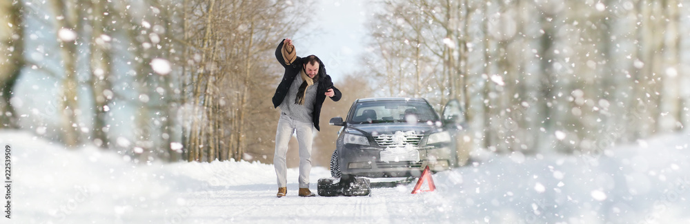 A man near a broken car on a winter day