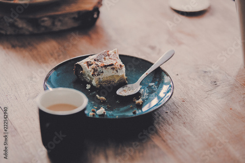 Plate with eaten cake and spoon on wooden table. Side view