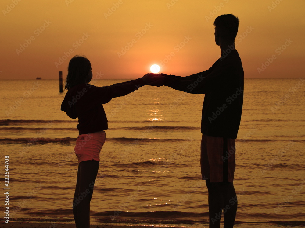 Fototapeta premium sagome di persone in controluce sulla spiaggia al sorgere del sole