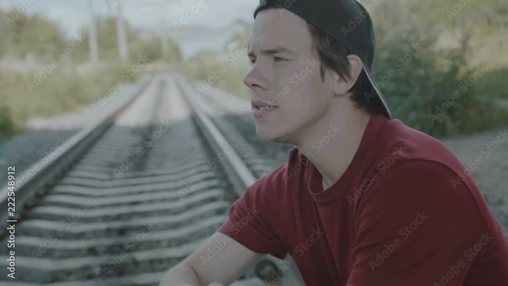 Young thoughtful boy sits on a rail and smokes cigarette. 4K Young thoughtful boy sits on a rail and smokes cigarette. 4K