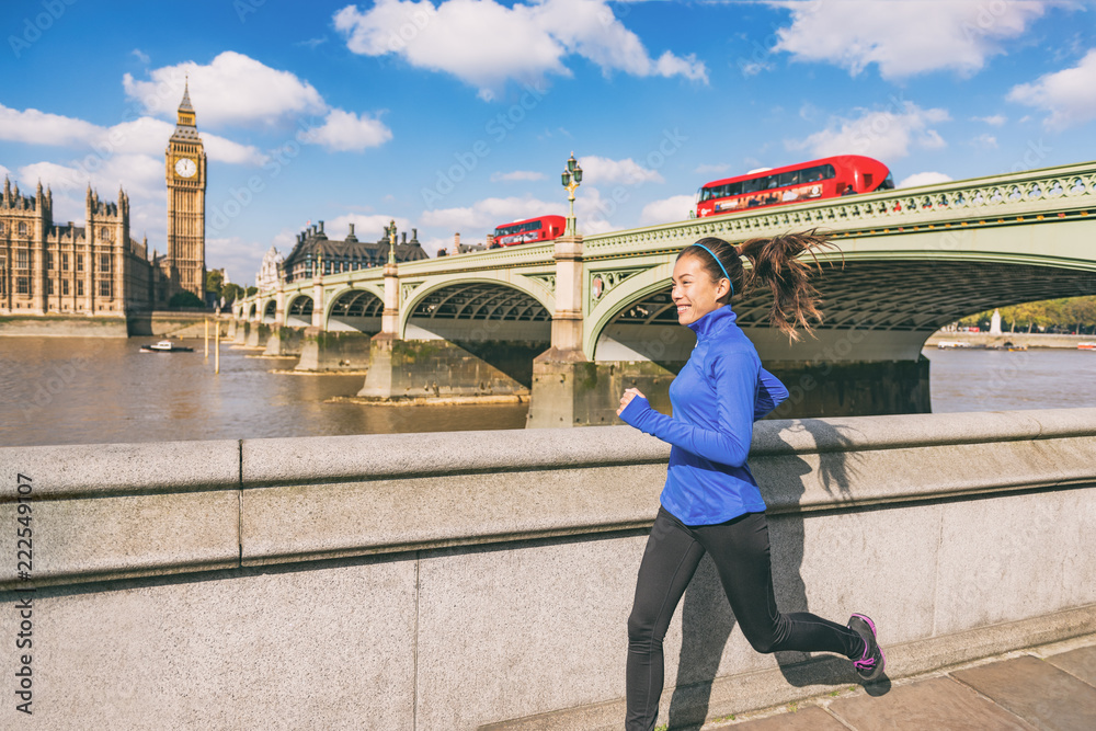 Naklejka premium London runner woman running near Big Ben. Europe city Asian girl jogging training at Westminster bridge with red double decker bus. Fitness athlete happy in London, England, United Kingdom.