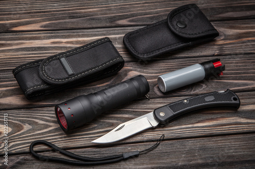 flashlight, pepper spray and knife on a wooden background. set for self-defense