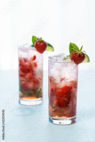 Strawberry mojito decorated with fresh strawberry, lime and mint. Blue background, high resolution.