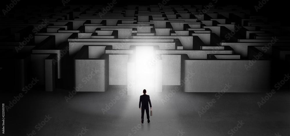 Lost businessman standing at the dark labyrinth with illuminated door
Lost businessman standing at the dark labyrinth with illuminated door