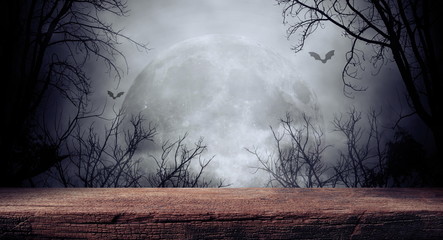Old wood table and silhouette dead tree at night for Halloween background.