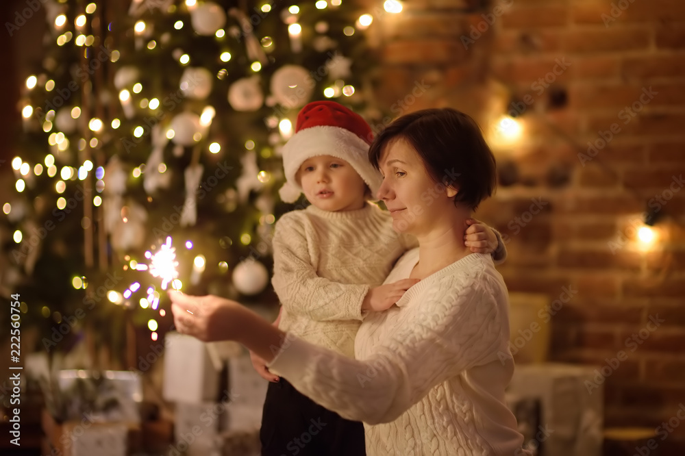Mother or grandmother with her little son or grandson celebration Christmas with sparkler