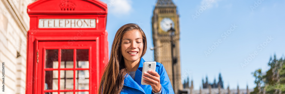 Fototapeta premium Londyński telefon kobiety odprowadzenie na miasto ulicy mienia telefonie komórkowym texting z brytyjskim krajobrazem, czerwonym telefonicznym budka i Big Ben Zegarowy wierza, Londyn, Anglia, UK. Panorama banera.