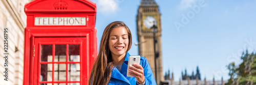London phone woman walking on city street holding cellphone texting with british landscape, red telephone booth and Big Ben Clock Tower, London, England, UK. Banner panorama.