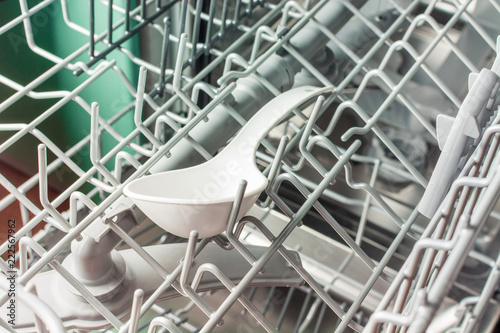 A white plastic cookware lies in the middle compartment of the dishwasher