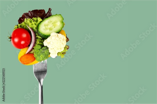 Fresh raw vegetables on fork on blue background