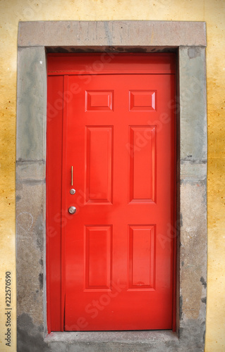 Colorful red wood door on rough wall © Julio