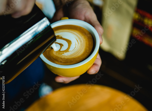 Barista pouring milk in coffee cup .