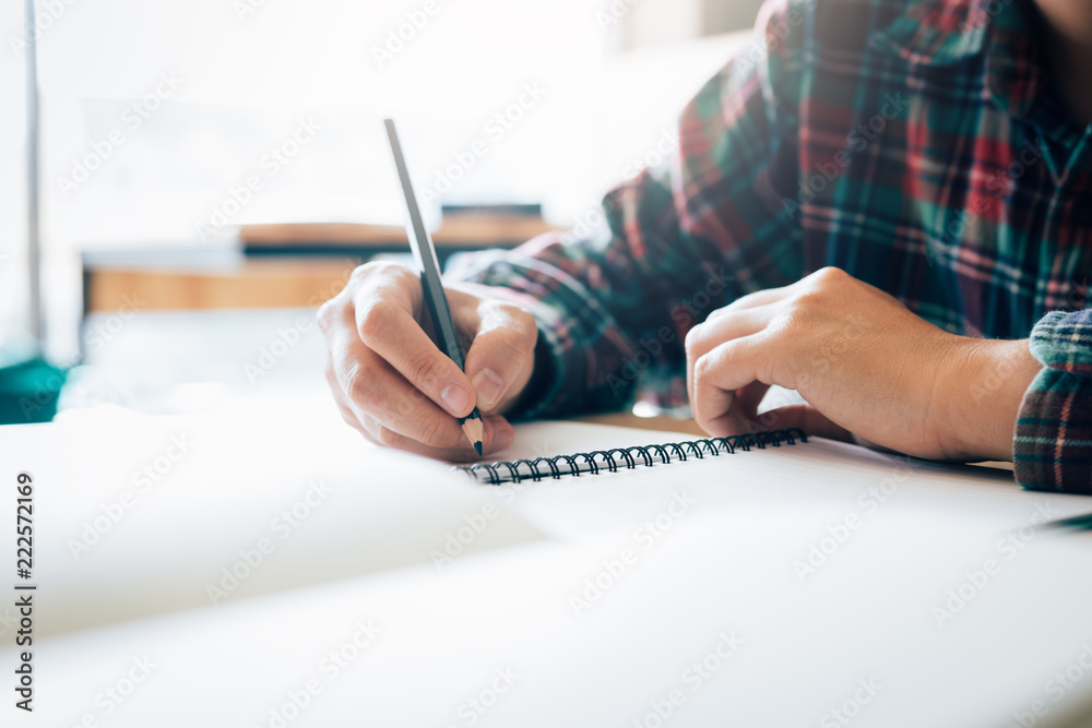 Teenage student works on homework in his room and writing in notebook. - obrazy, fototapety, plakaty 