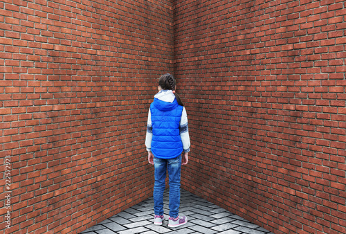 Punished little girl is standing in a corner photo