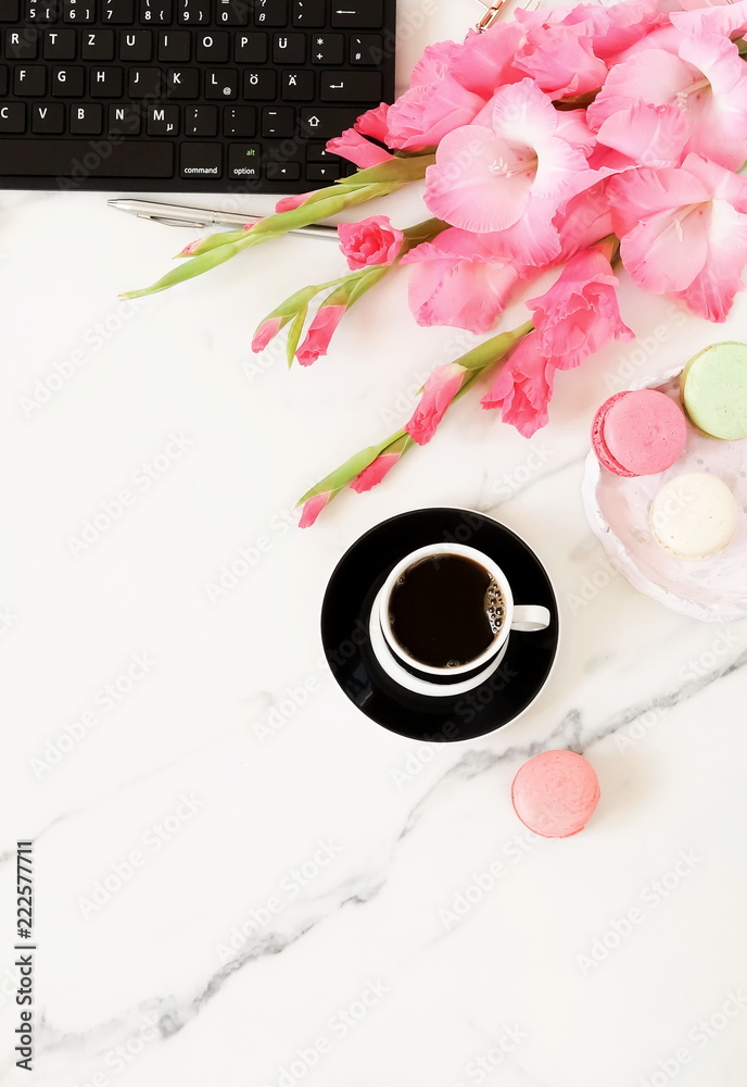 Flat lay women's office desk. Female workspace with laptop, flowers pink gladioluses , accessories, glasses, cup of coffee on marble desk background. Top view feminine background.Copy space Flat lay women's office desk. Female workspace with laptop, flowers pink gladioluses , accessories, glasses, cup of coffee on marble desk background. Top view feminine background.Copy space