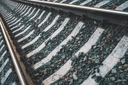 Minimalist background of diagonal railroad at dusk with copy space. Rails, sleepers, fastenings and crushed stone close up. Railway traveling. Journey on rail track. Pattern in dark blue tones.