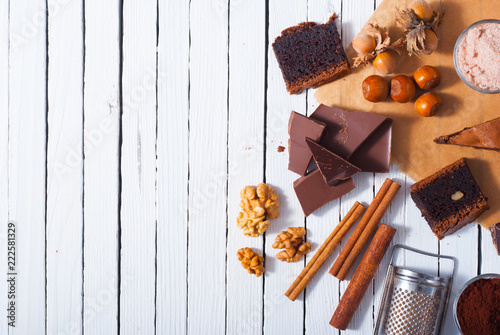 chocolate brownie cake and ingredients, baking papaer on white wood table background photo