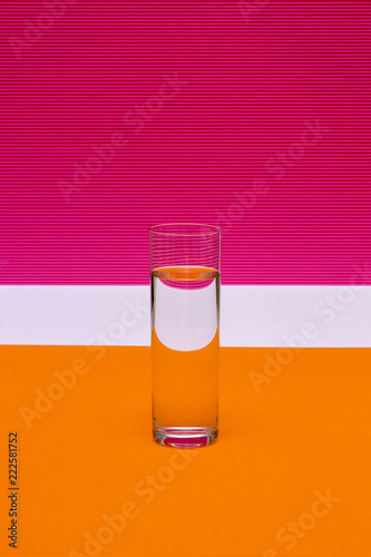 Glass with a glass of liquid on a colored background