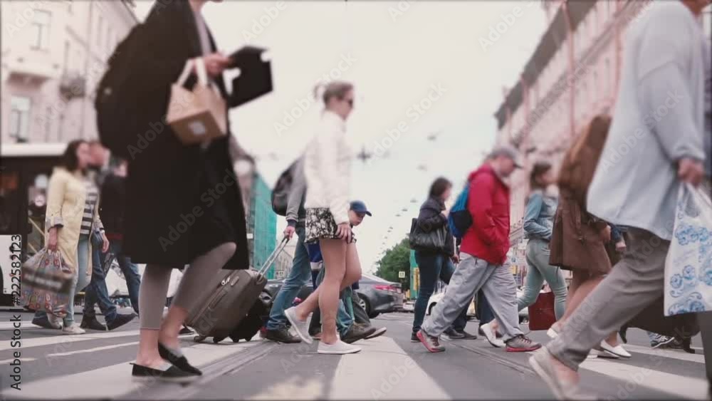 Slow motion shot of anonymous big crowd walking across a busy old city street with buses and cars in Saint Petersburg.