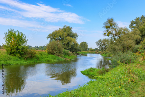 View of small river against blue sky in autumn morning. River landscape