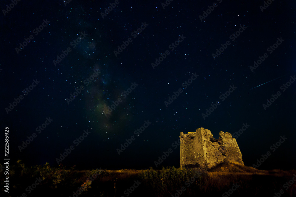 Nightscape with milky way and shooting star and an old ruin of a tower as foreground.