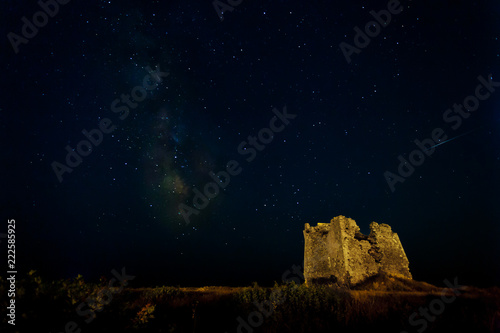 Nightscape with milky way and shooting star and an old ruin of a tower as foreground.