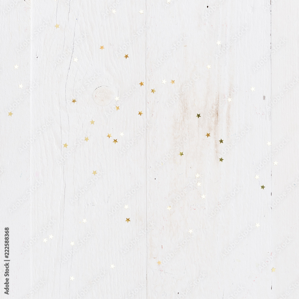 Obraz premium Closeup of golden stars confetti on vintage white wooden background. Winter, Christmas celebration, holidays season concept