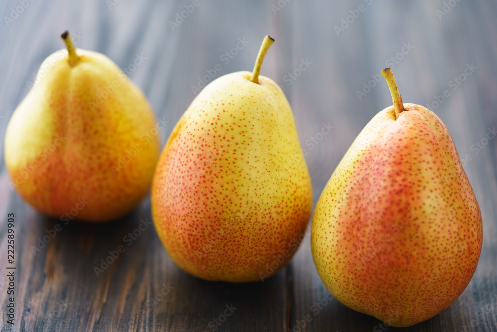 Three fresh pears on a dark wooden background. Backlight, selective focus, high resolution. Three fresh pears on a dark wooden background. Backlight, selective focus, high resolution.