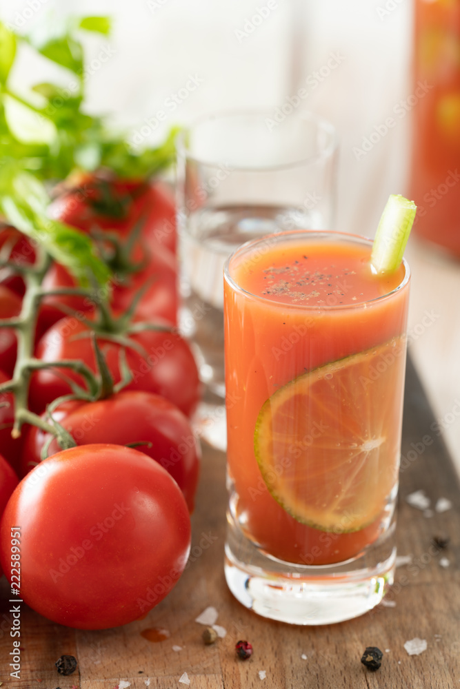 Sangrita in a shot glass served with fresh tomatoes, celery sticks and black pepper. Tequila bottle in bokeh, wooden board, high resolution. Sangrita in a shot glass served with fresh tomatoes, celery sticks and black pepper. Tequila bottle in bokeh, wooden board, high resolution.