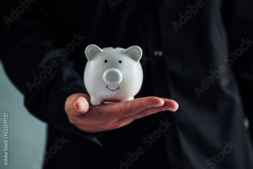 Businessman in suit is holding piggy bank. Finance Savings concept