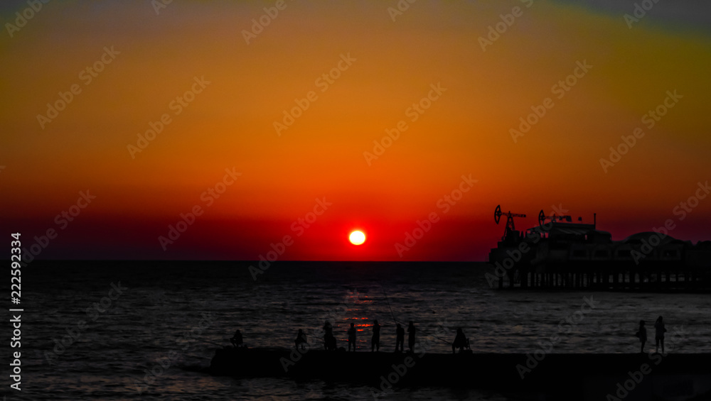 Obraz premium Fishermen on sunset background in the sea