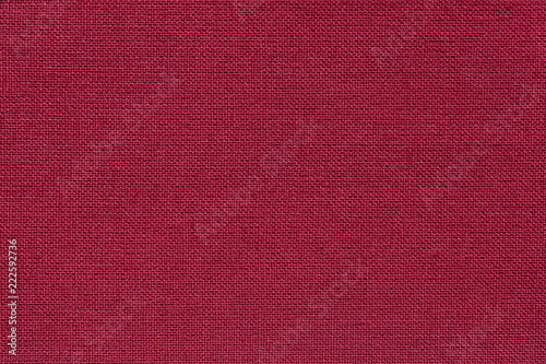 Dark red background from a textile material with wicker pattern, closeup.
