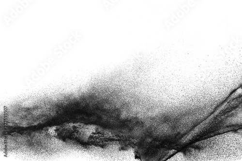 Black particles splattered on white background. Black powder dust splashing. photo