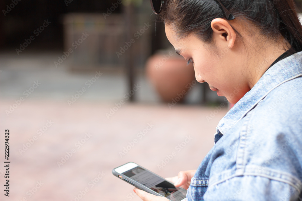 Behine girl wearing a jacket, jeans and orange shirt and playing mobile phones. Behine girl wearing a jacket, jeans and orange shirt and playing mobile phones.