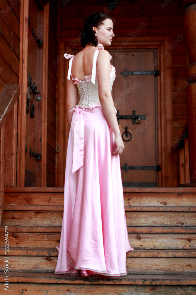 Fine emotional brunette on old style veranda, full length. Yonge girl in vintage pink pastel with live expressions on beautiful country and old background.
