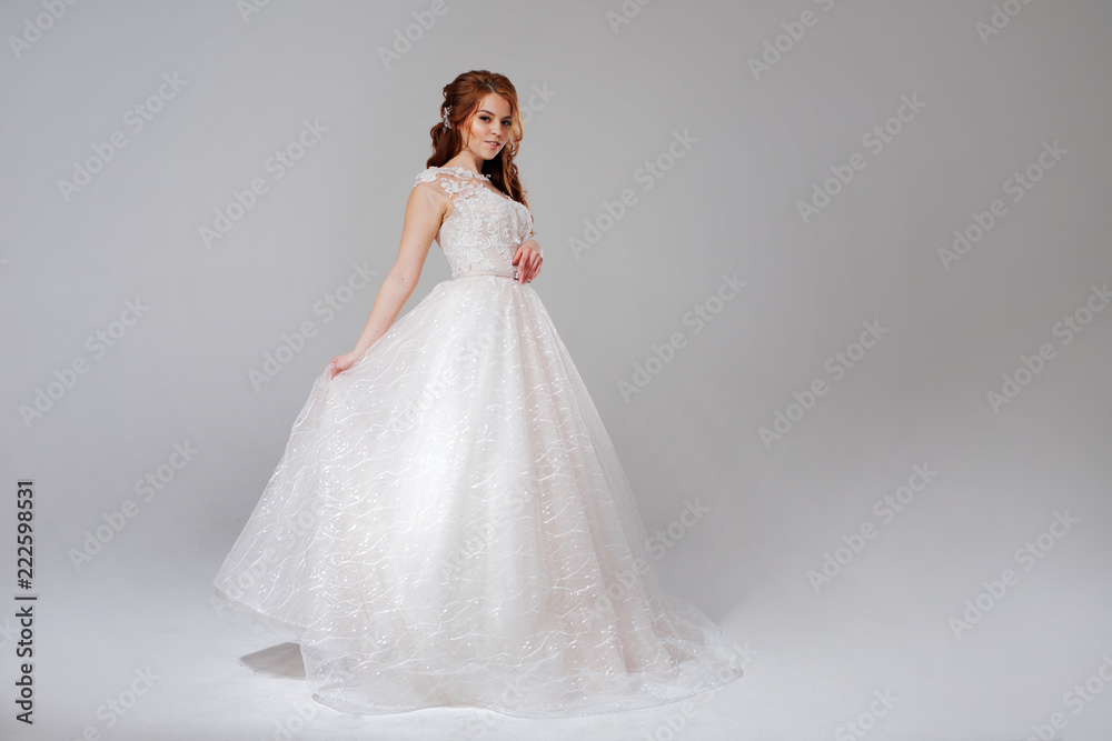 Lovely young woman bride in lavish wedding dress. Light background.