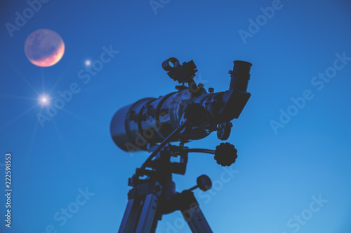 Telescope silhouette on a twilight sky with few stars. Moon and stars are defocused / blurred. My astronomy work.