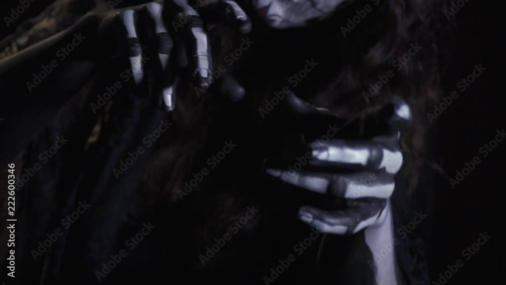 Eerie dead bride with a wreath of roses, posing in the dark and pulling her hands towards the camera Eerie dead bride with a wreath of roses, posing in the dark and pulling her hands towards the camera