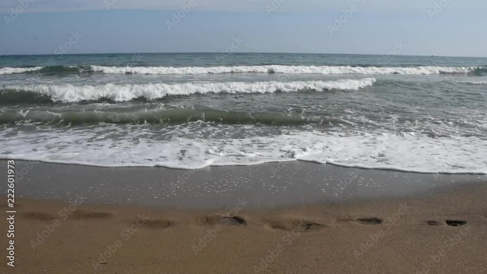 Seascape with waves and footsteps on the beach Seascape with waves and footsteps on the beach