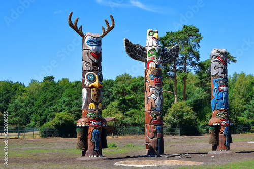 Foto Three colorful wooden totem poles on green trees and blue sky background outdoors in park
