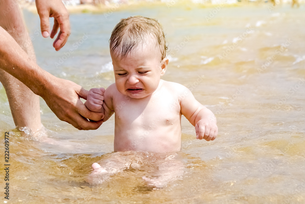 Frozen and crying boy sitting in water. Recreation, holidays, vacation Frozen and crying boy sitting in water. Recreation, holidays, vacation