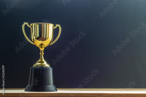 trophy on top of old wooden table in front of blackboard.