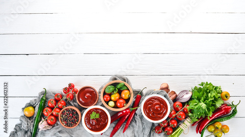 Fototapeta Naklejka Na Ścianę i Meble -  Preparation of tomato sauces and seasonings. Cherry tomatoes, spices, chili peppers. Top view. On a white wooden background. Free copy space.